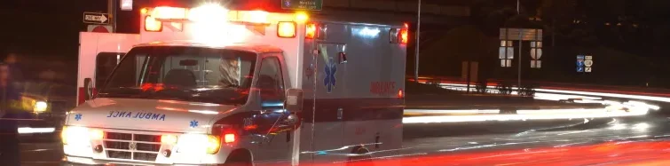 A blurry ambulance driving down the street at night.
