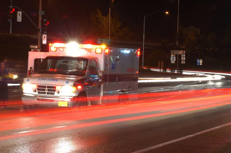 A blurry ambulance driving down the street at night.