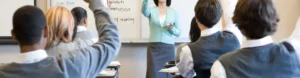 A woman standing in front of a class with her hands raised.