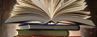 A book is open on top of some books.