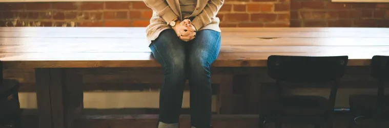 A woman sitting on top of a wooden bench.