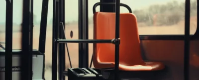 A bus seat with the arm rest folded up.