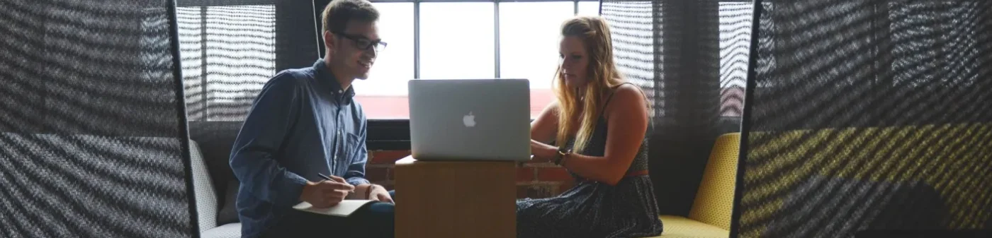 Two people sitting on a couch with laptops