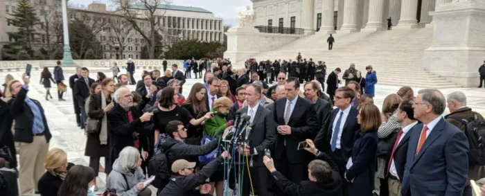 A crowd of people gathered around a microphone.