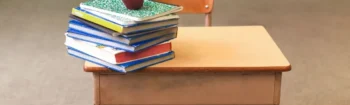 A stack of books and an apple on top of a desk.