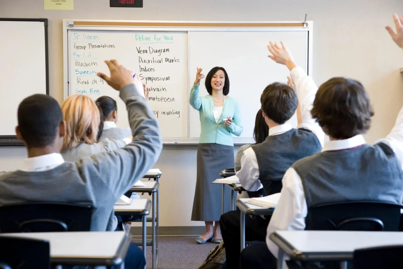 A woman standing in front of a class with her hands raised.