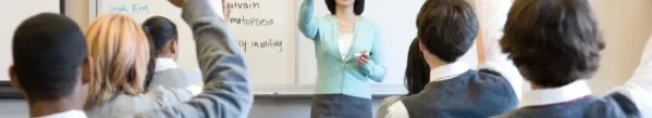 A woman standing in front of a class with her hands raised.