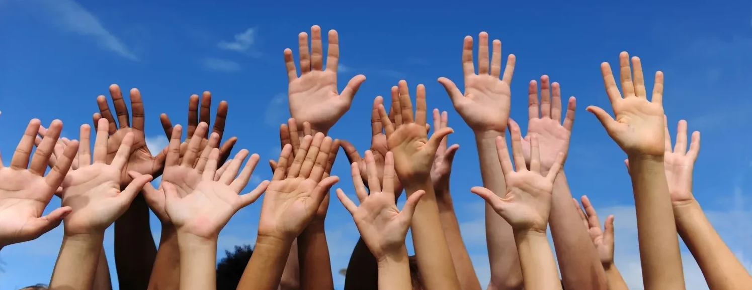A group of people raising their hands in the air.