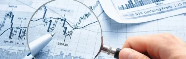 A person holding a magnifying glass over some graphs