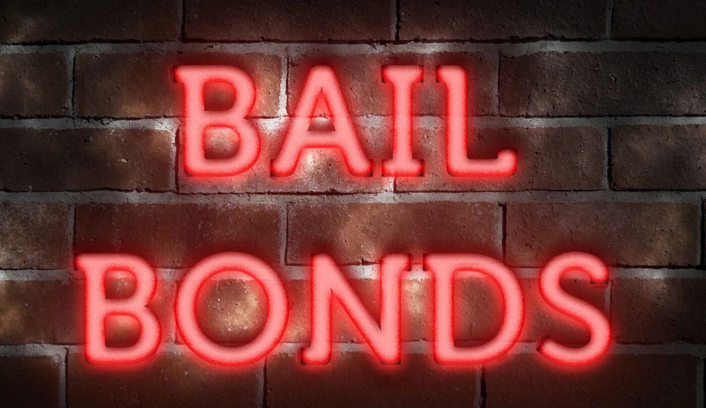 A brick wall with neon sign that says bail bonds.