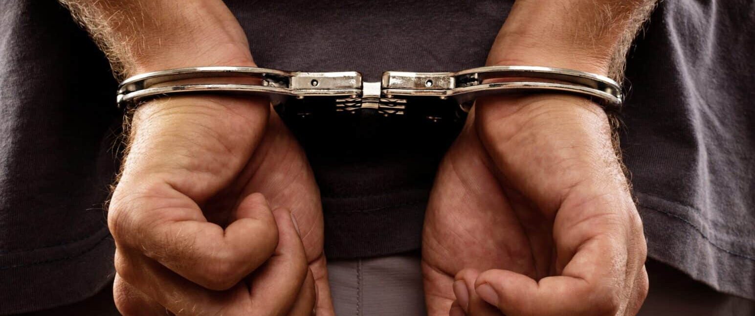 Close-up. Arrested man handcuffed hands at the back