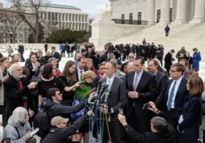 A crowd of people gathered around a microphone.
