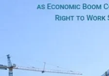 A crane is in the sky with buildings behind it.