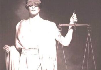 A woman holding a scale and blindfold in front of her face.