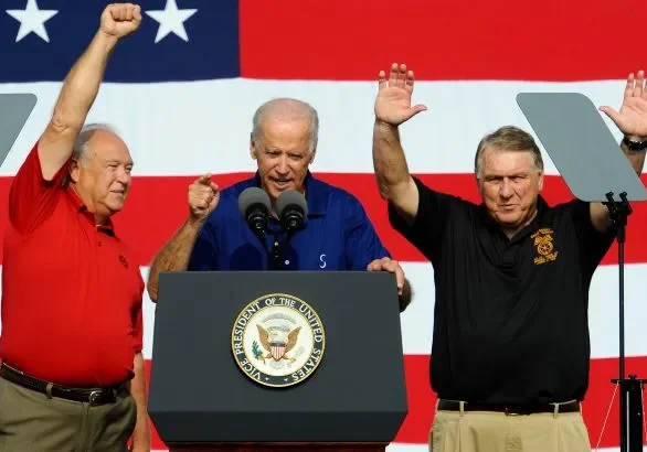 Three men standing at a podium with one man raising his fist.