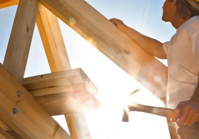 qtq80-1SkkXB A man in yellow hard hat working on wooden structure.