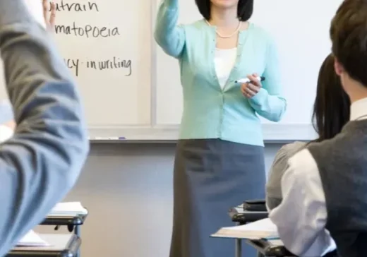 A woman standing in front of a class with her hands raised.