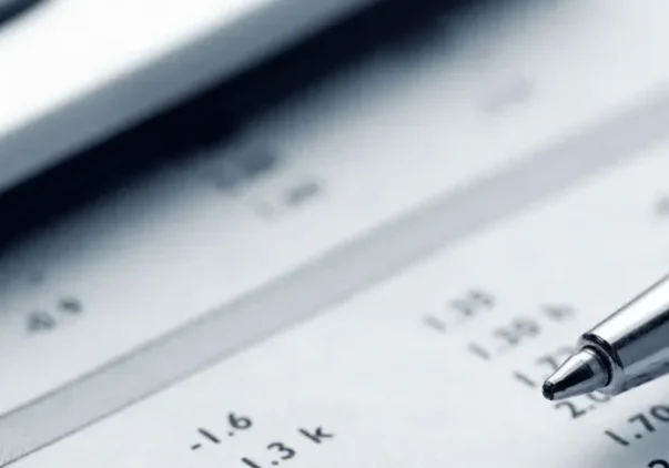 A calculator and pen on top of some paper