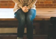 A woman sitting on top of a wooden bench.