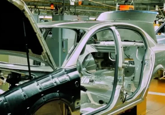 qtq80-IwdSgE A car assembly line with cars in the process of being built.