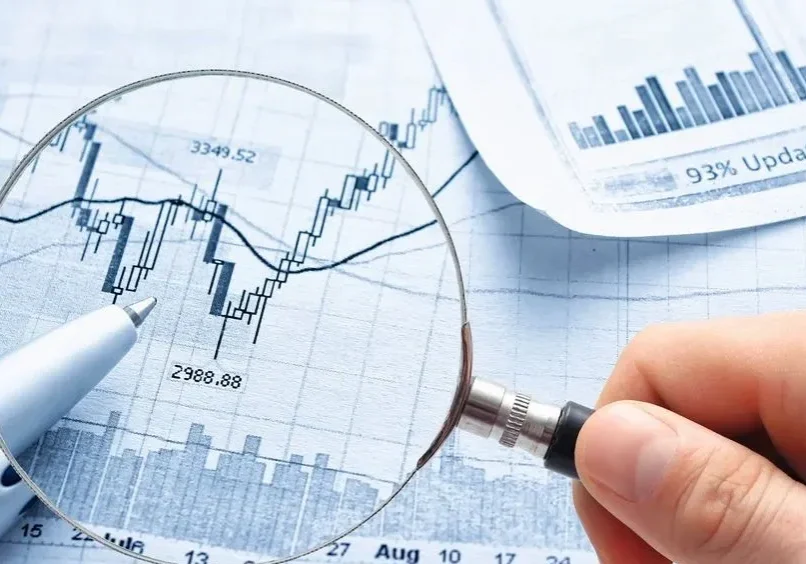 A person holding a magnifying glass over some graphs