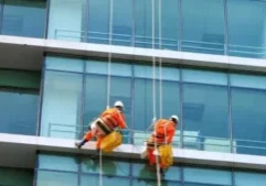 Two men hanging from ropes on a building.