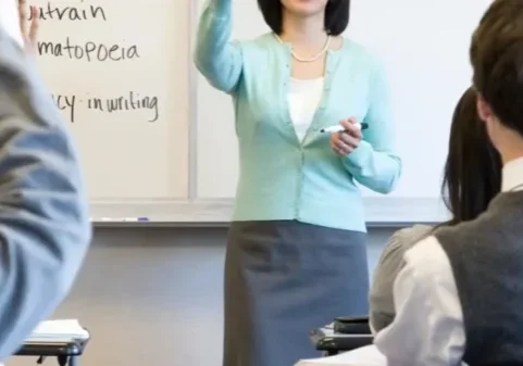 qtq80-ankWS8 A woman standing in front of a class with her hands raised.