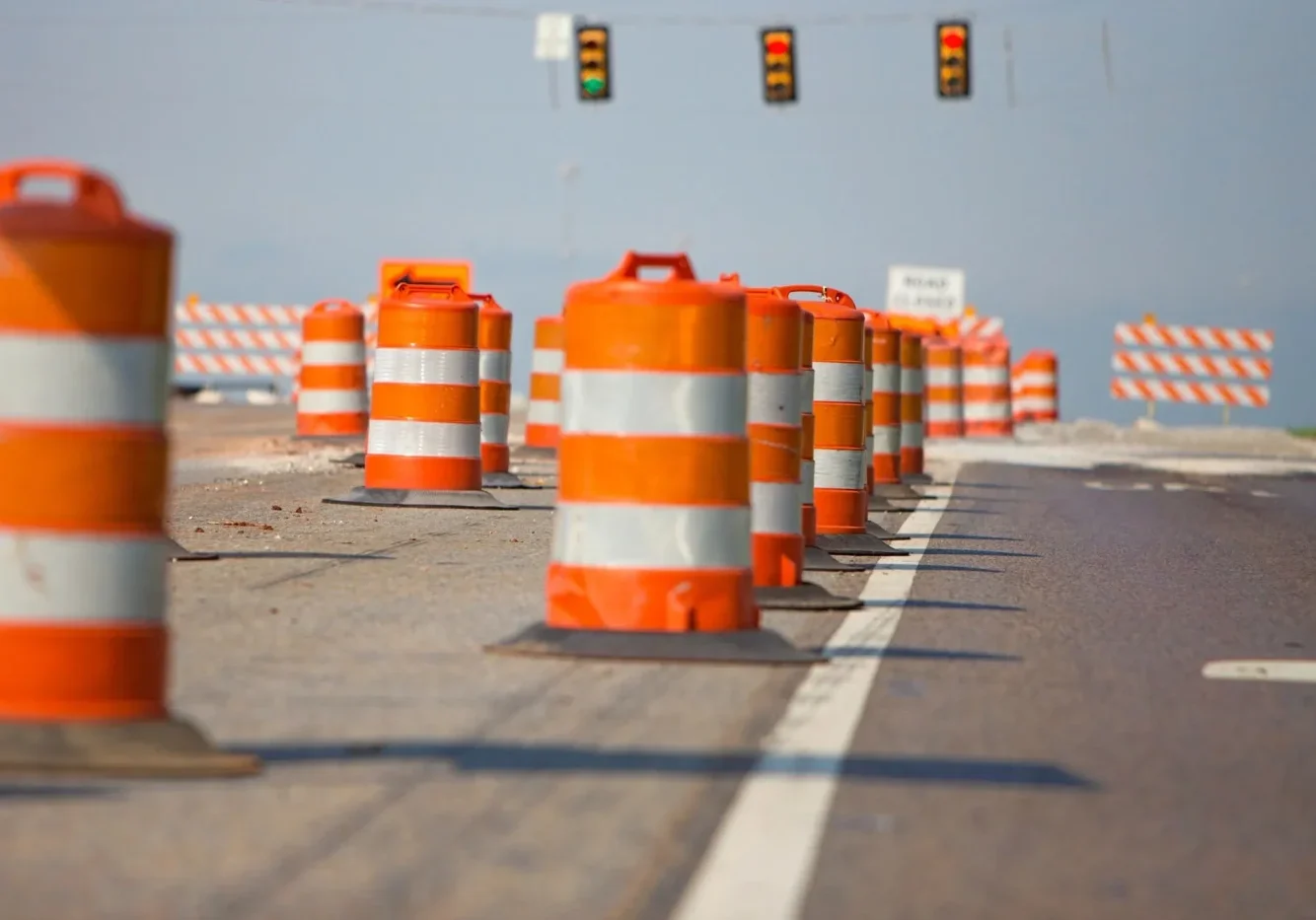 A bunch of orange and white barrels on the side of the road