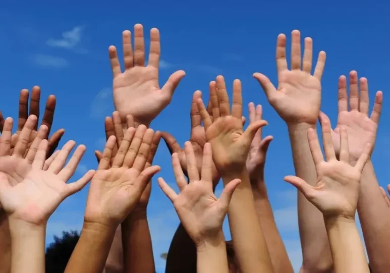 A group of people raising their hands in the air.