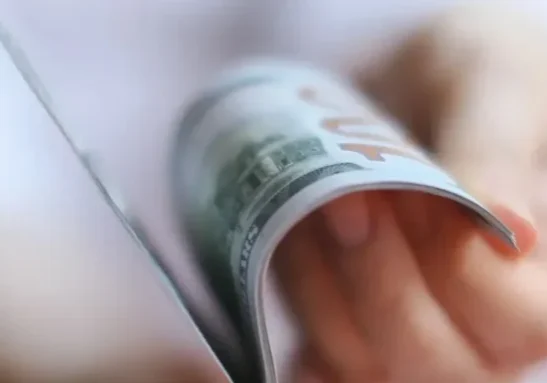 A person holding a dollar bill in their hands.