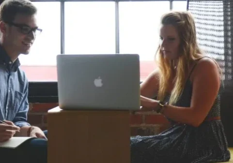 Two people sitting on a couch with laptops