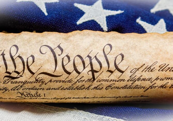 Rolled up copy of the US Constitution with a vintage American flag on white painted weathered wood